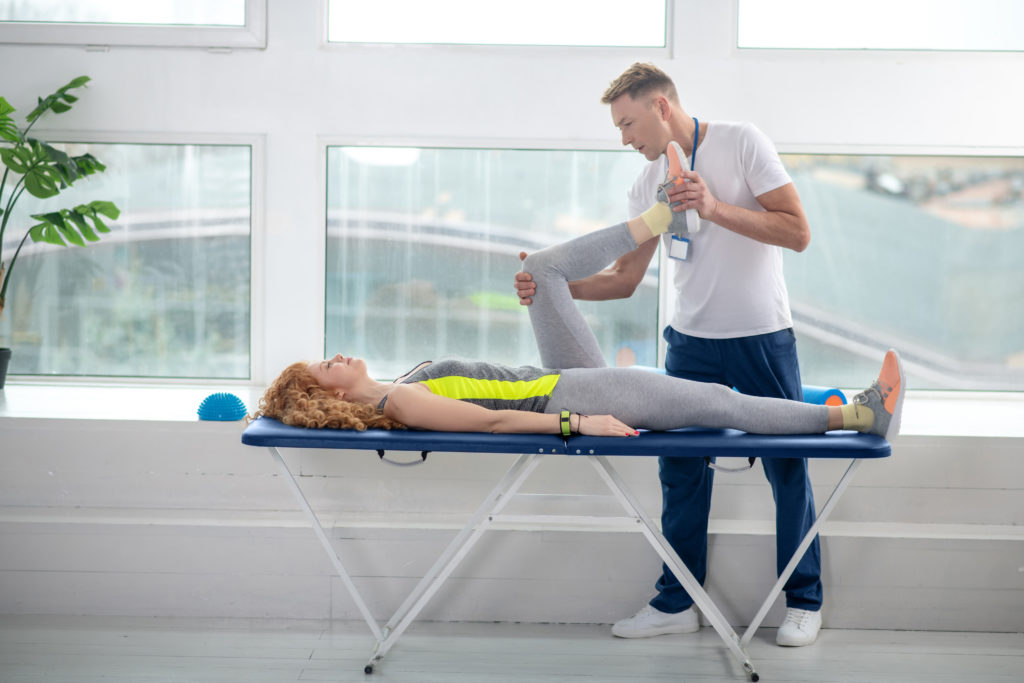 Male physiotherapist treating leg of female patient